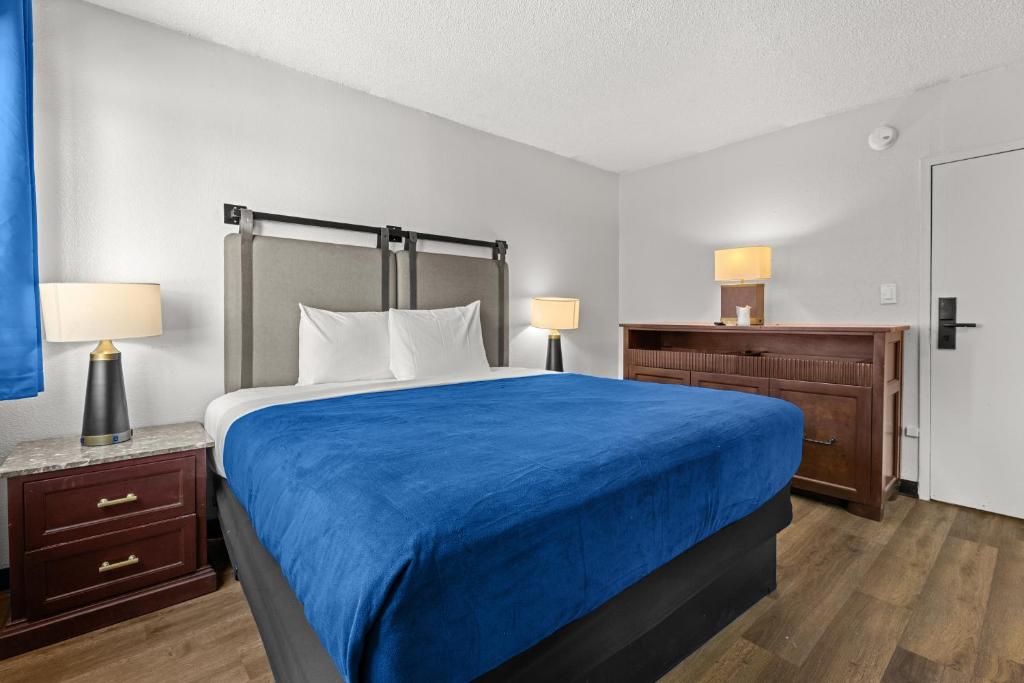 a bedroom with a large bed with a blue blanket at Studio Lodge Hotel in Hewitt