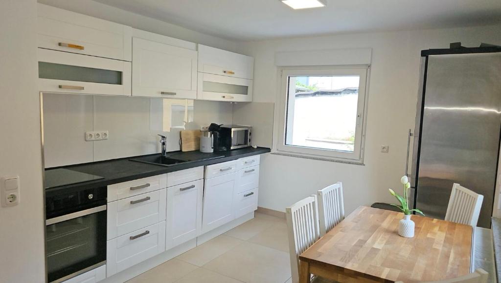 a kitchen with white cabinets and a wooden table at Wambacher Ferienwohnung in Schlangenbad