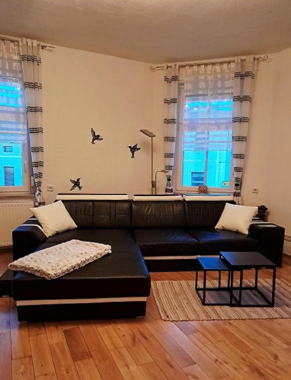 a living room with a black couch and two windows at Wohlfühloase in der City in Luckenwalde