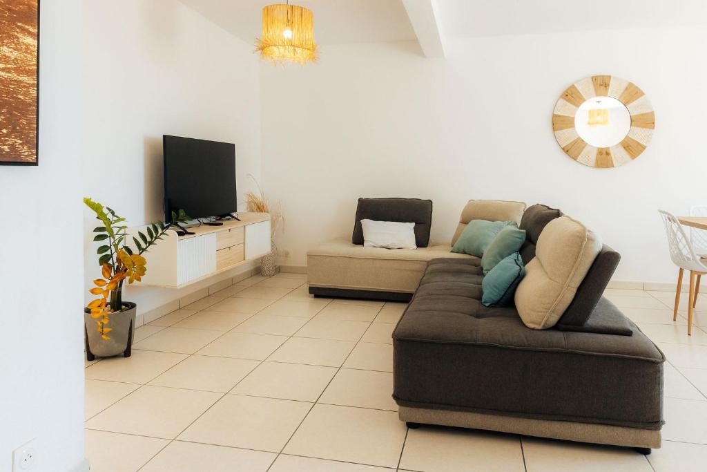 a living room with a couch and a tv at Villa du Ruisseau in Saint-Louis