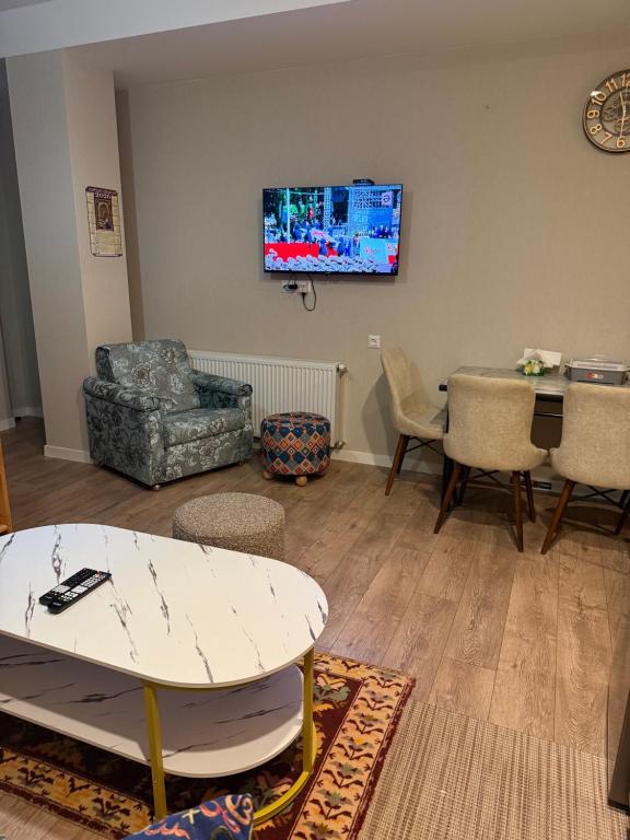 a living room with a table and a tv on the wall at Nino's Home in Bakuriani