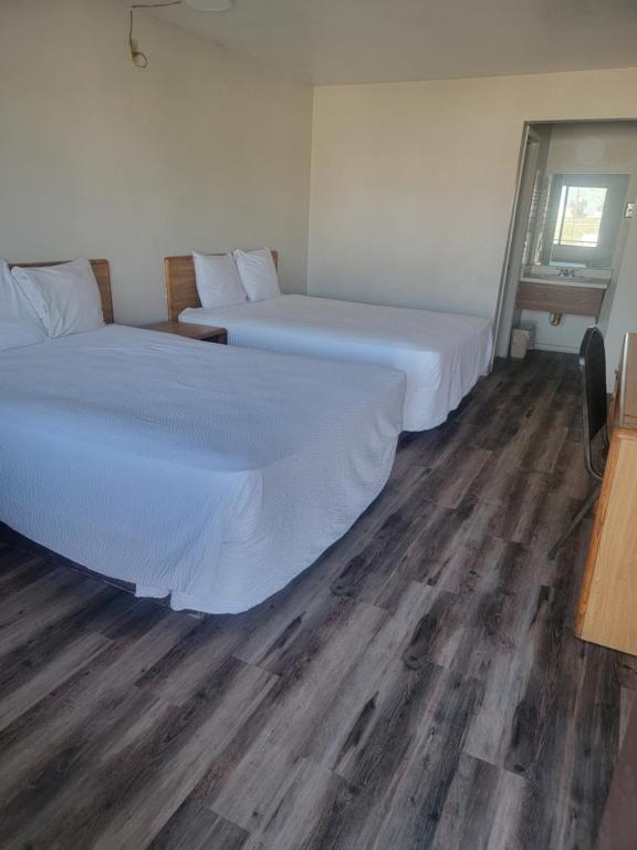 two beds in a room with wooden floors at Best Economy Inn & Suites in Bakersfield