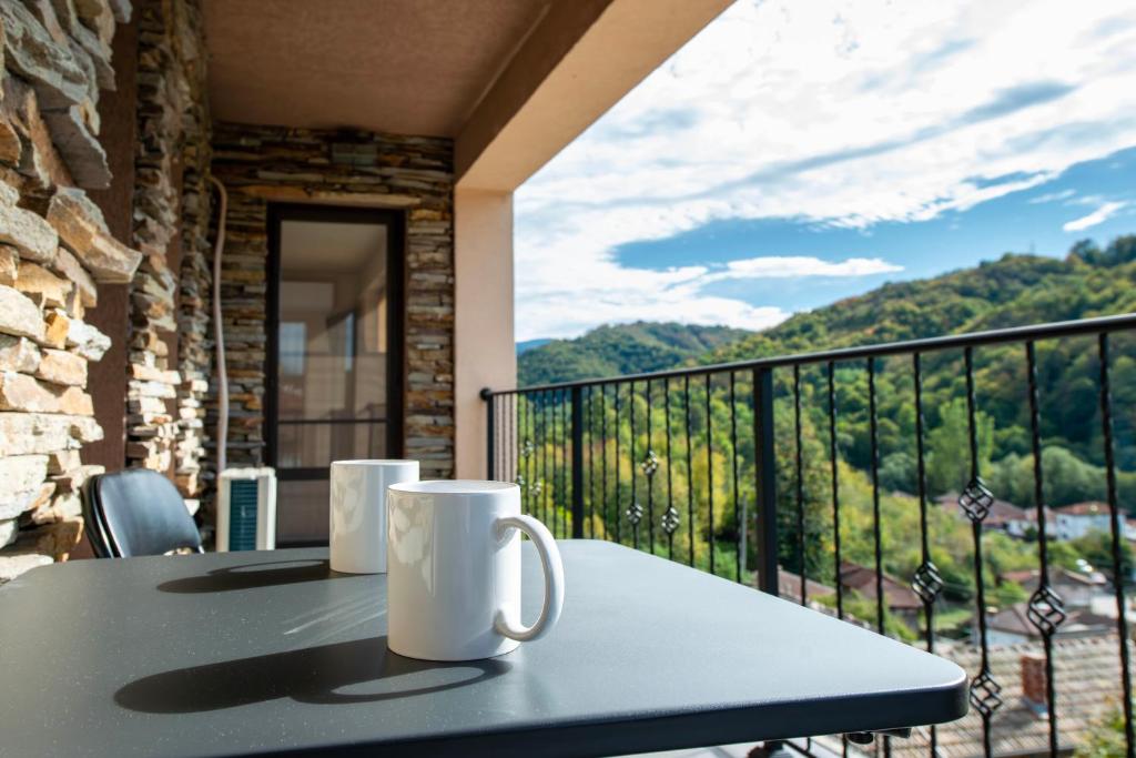 a table with two mugs on a balcony with a view at Къща за гости Трявна in Tryavna