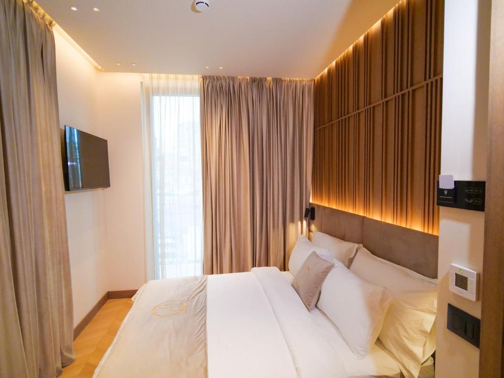 a bedroom with a large white bed and a window at Post Inn Hotel-New Bazaar in Tirana