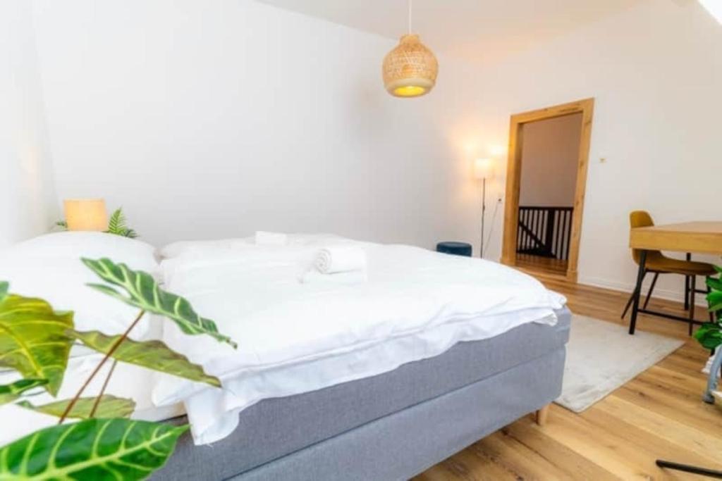 a bedroom with a bed with white sheets and a plant at Lykke Suite in Handewitt
