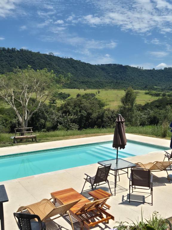 a swimming pool with chairs and a table next to it at Ecofazenda Lodge in Bofete