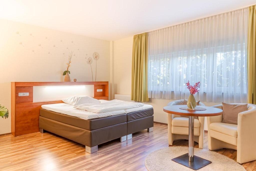 a bedroom with a bed and a table and chairs at Hotel Victoria in Hochheim am Main