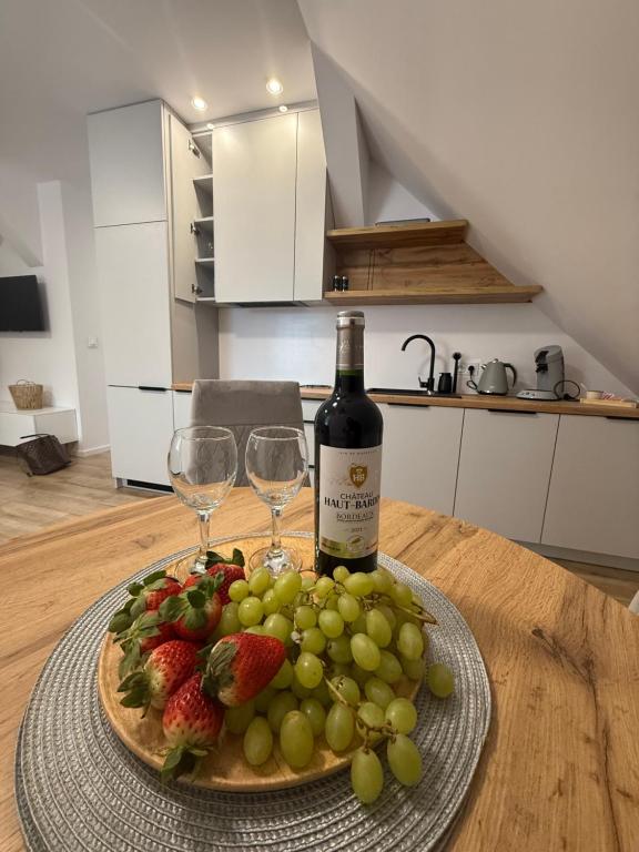 a plate of fruit with a bottle of wine and two glasses at MICKIEWICZ HOUSE Apartamenty in Wadowice
