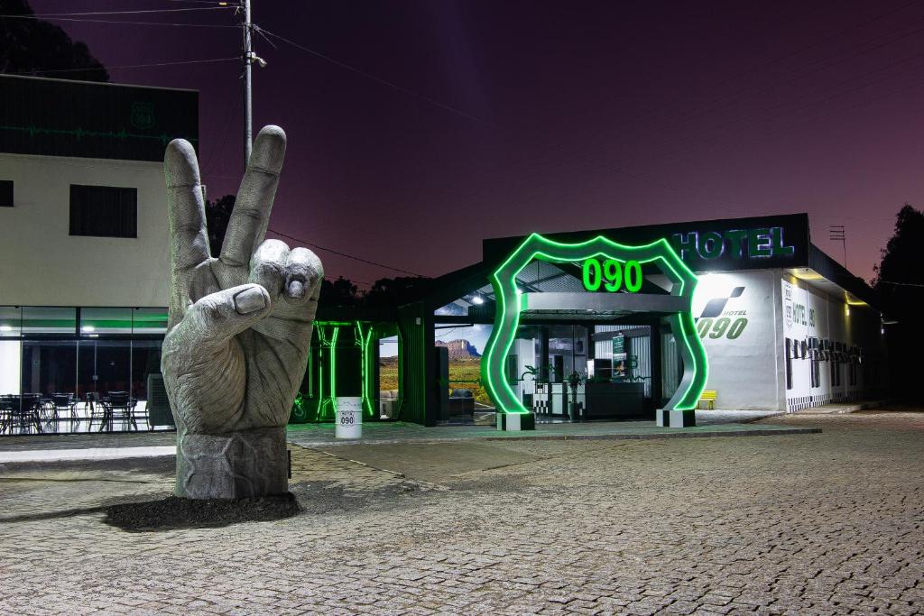 a statue of a waving hand in front of a gas station at Hotel Rota 090 in Piraí do Sul