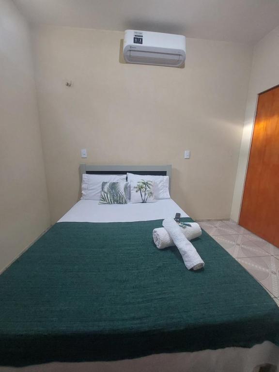 a bedroom with a large bed with a green blanket at Residence tropical, disponível 2 quartos para alugar in Guriú