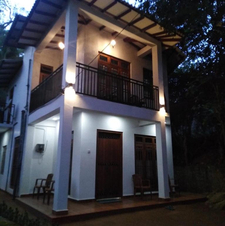a house with a balcony and two chairs in front of it at Lake parth Giritale in Giritale