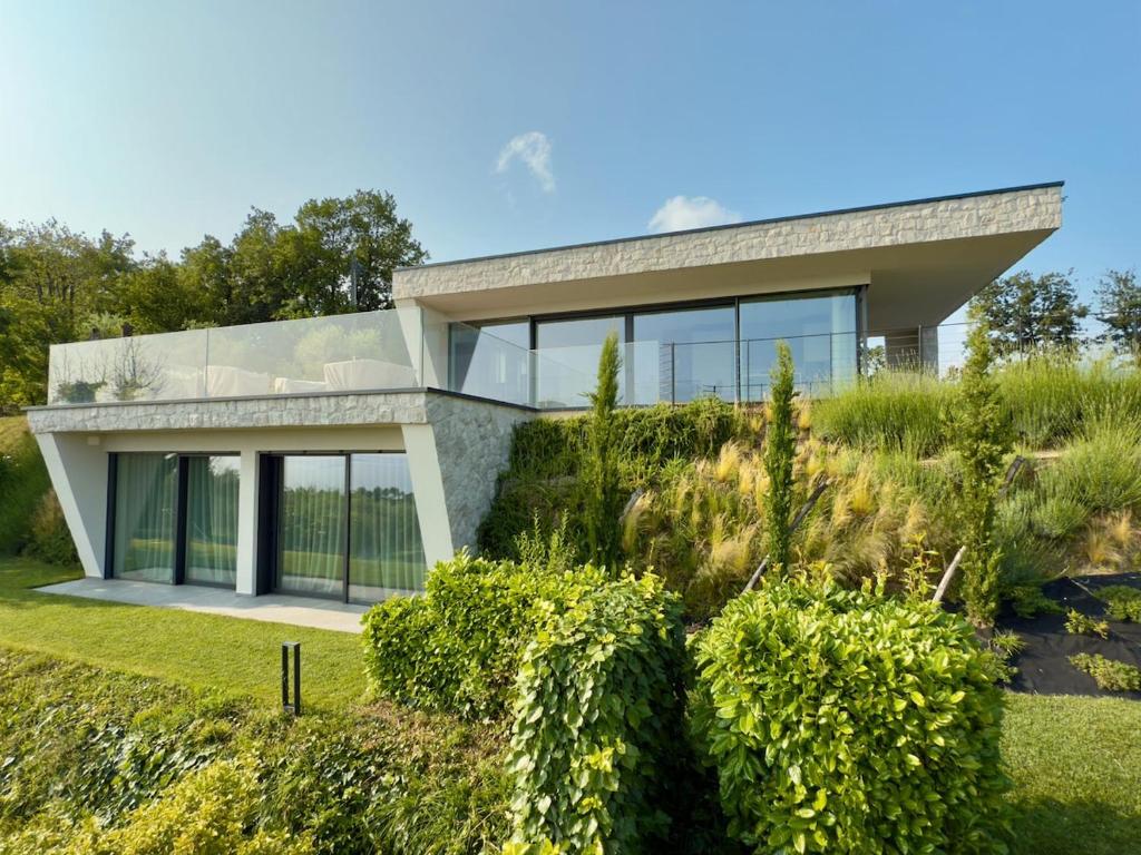 a modern house with glass windows and bushes at Villa Vallonga in Bardolino