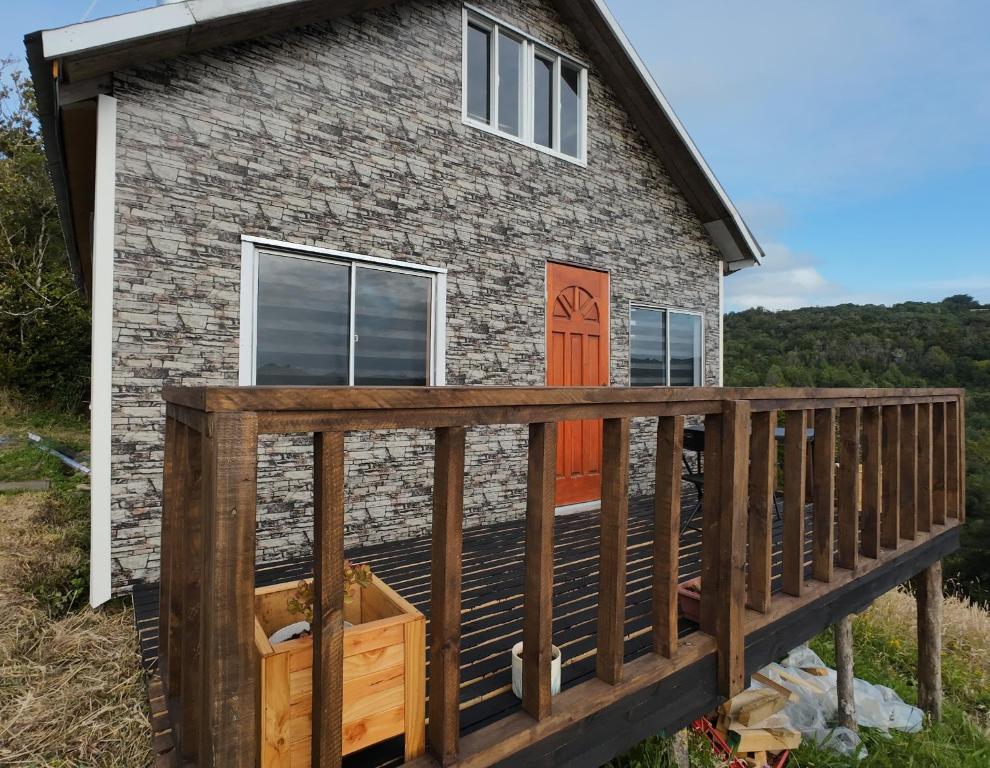 a home with a deck and a house at Cabañas Victoria Aucaco in Ancud
