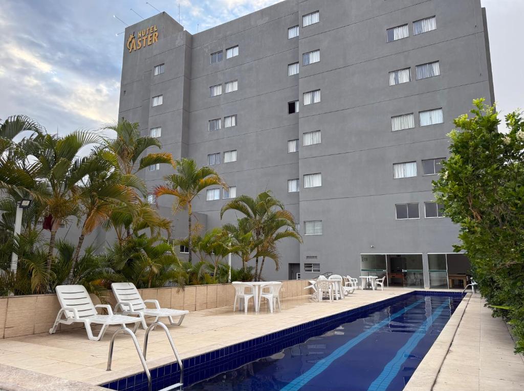 a hotel swimming pool with chairs and a building at Hotel Áster in Alagoinhas