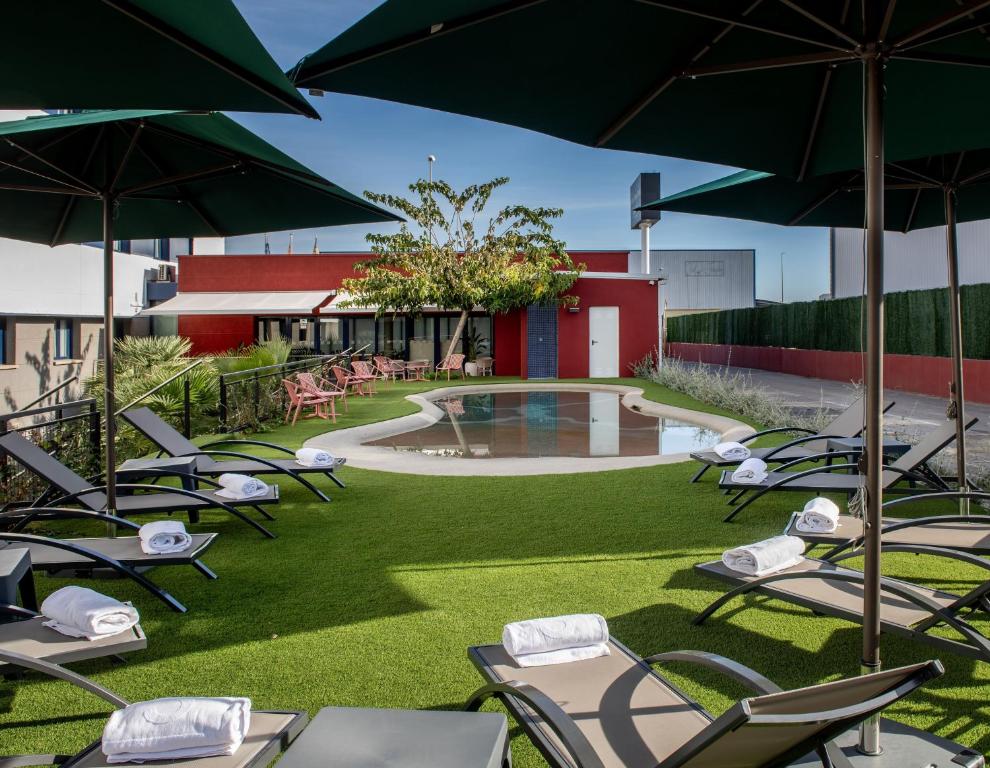 a group of lawn chairs with umbrellas and a pool at Hotel Sercotel Plana Onda in Onda