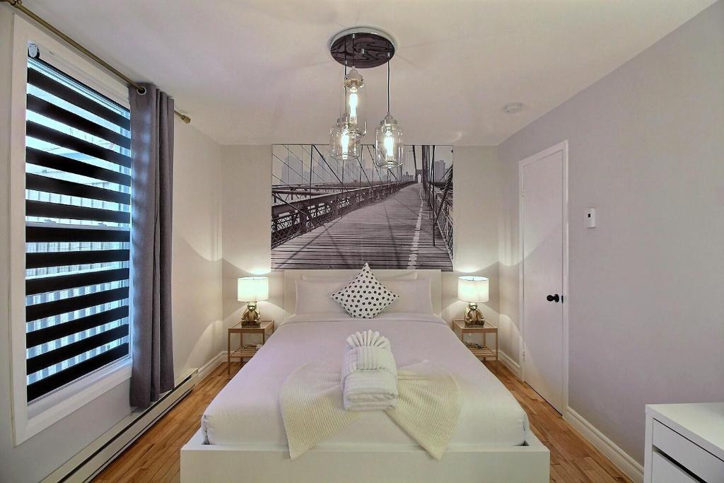 a bedroom with a white bed with a bridge mural on the wall at Bluenose in Quebec City