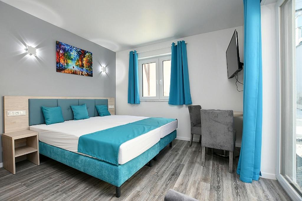 a bedroom with a bed and a desk and a tv at City-Hotel Zuffenhausen - Apartments in Stuttgart