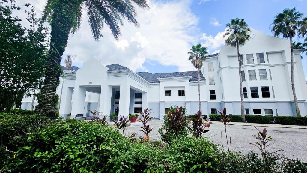 a white house with palm trees in front of it at Montreal Suites Orlando in Orlando