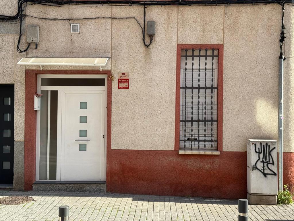 a building with a white door and two windows at Habitaciones Carmen in Rubí