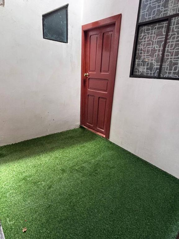a red door on the side of a building with green grass at Triple B in Loja