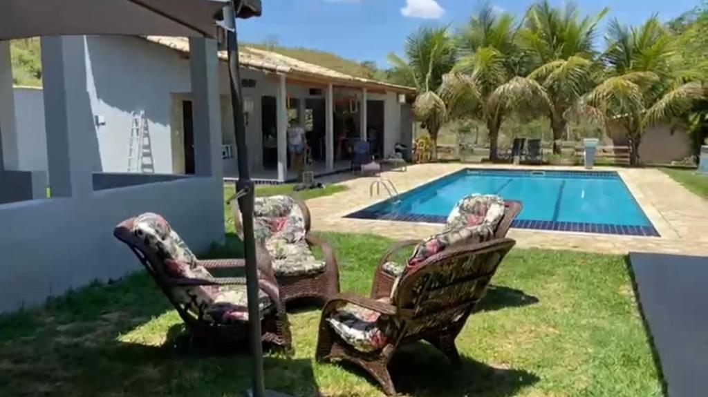 a house with two chairs and a swimming pool at chácara vale do sol in Valença