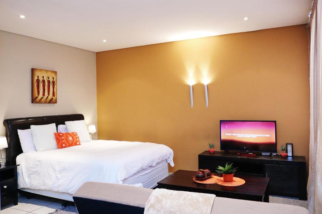 a bedroom with a bed and a flat screen tv at The Orange Corner II in Johannesburg