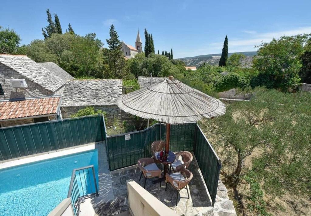 a patio with an umbrella and chairs next to a pool at House Niksi in Škrip