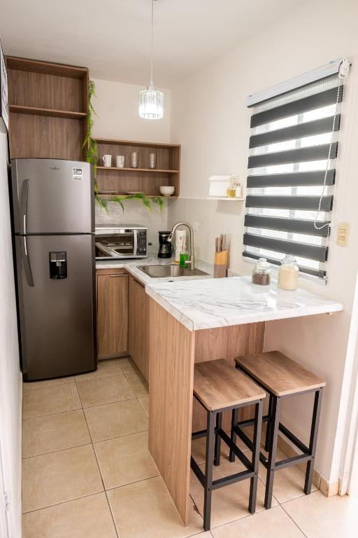 a kitchen with a refrigerator and a table with stools at Loft Montecarlo in Hermosillo