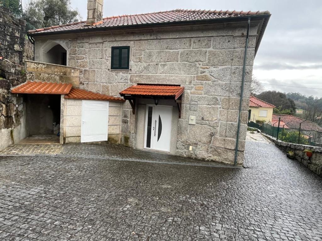 a stone building with two white doors on a cobblestone street at Casa da Ramada - Water SPA Tank with running natural spring water - by Bedzy in Braga