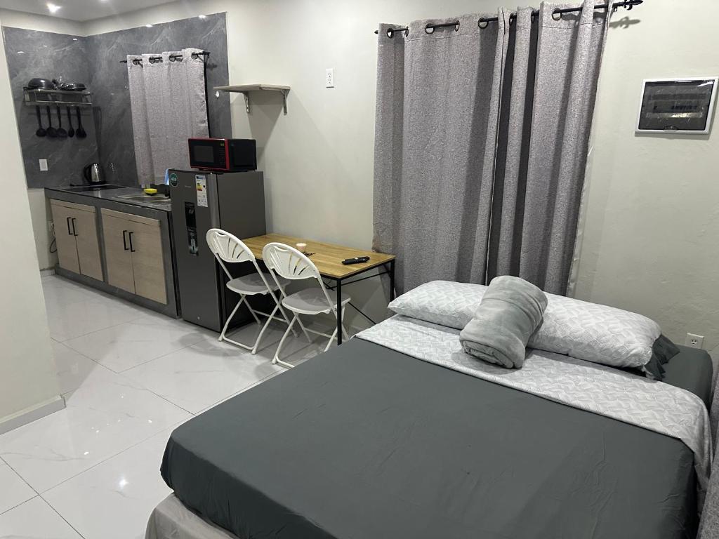 a bedroom with a bed and a table and a kitchen at Prestige Apartments C - Affordable Studio Near Sambil Shopping Mall with Fast WiFi in Willemstad