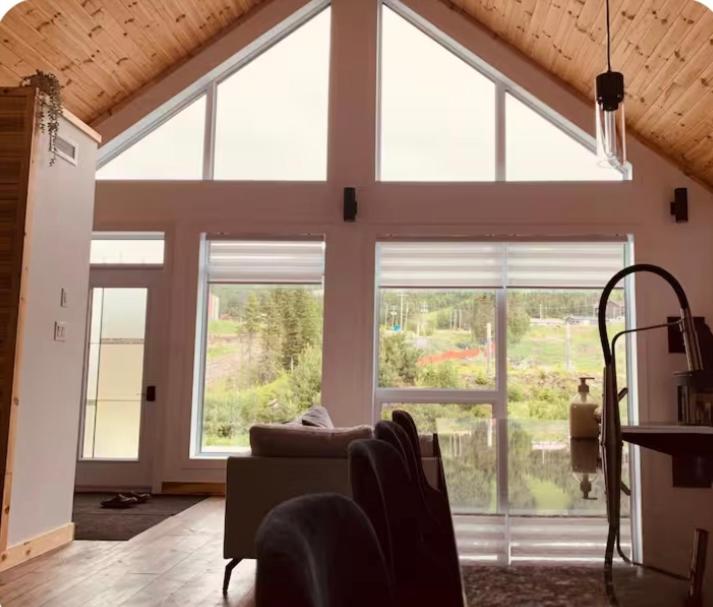 a living room with large windows and a couch at NOvO Chalet in Saint-David-de-Falardeau