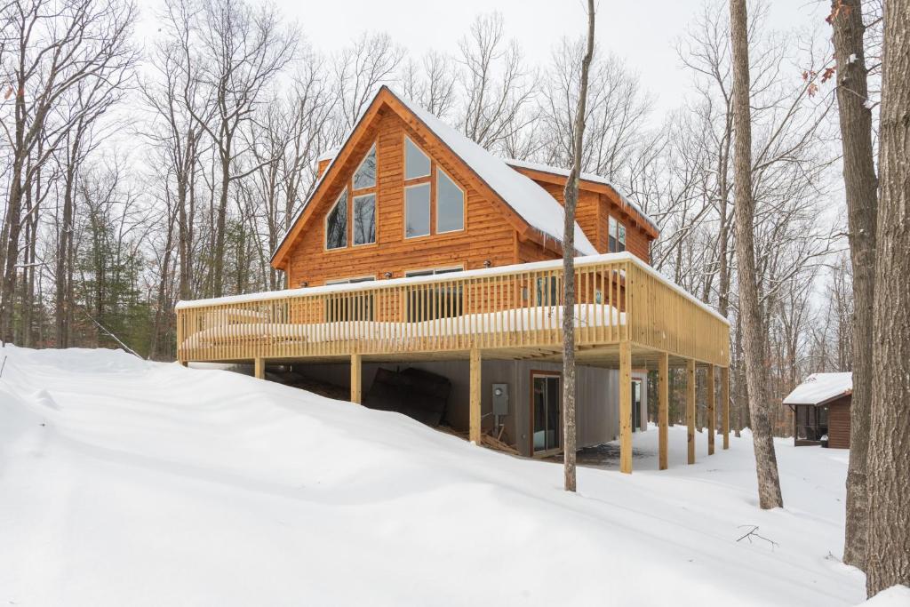 a wooden house in the woods in the snow at Lighthearted Lodge by Railey Vacations in Swanton