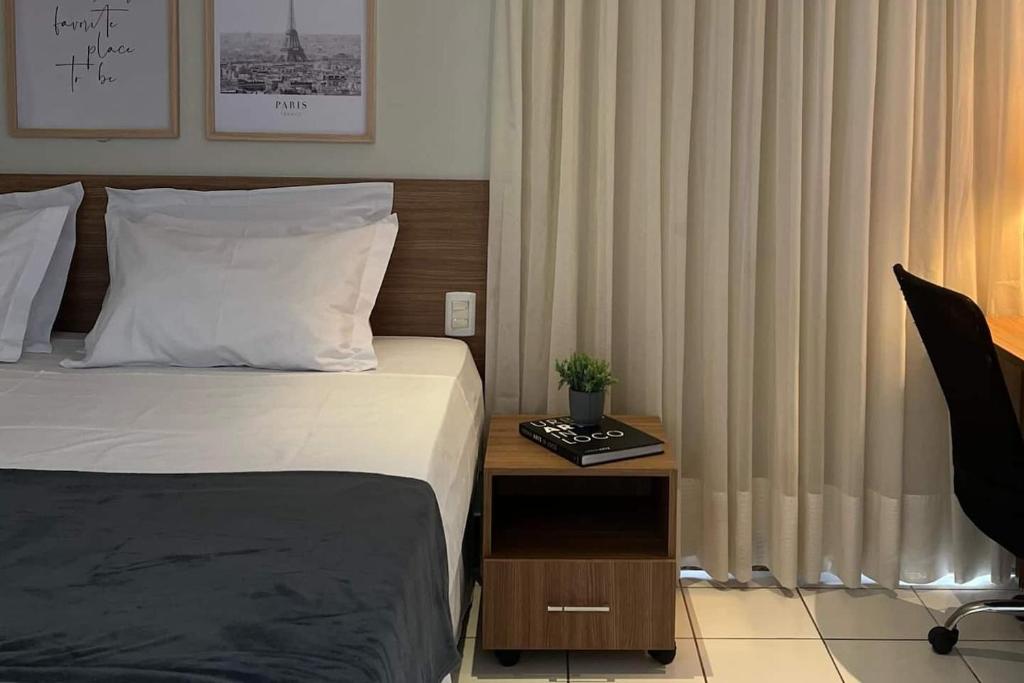a bedroom with a bed and a table with a night stand at St Oeste Superking Ar, Cozinha, Office, Vaga in Goiânia