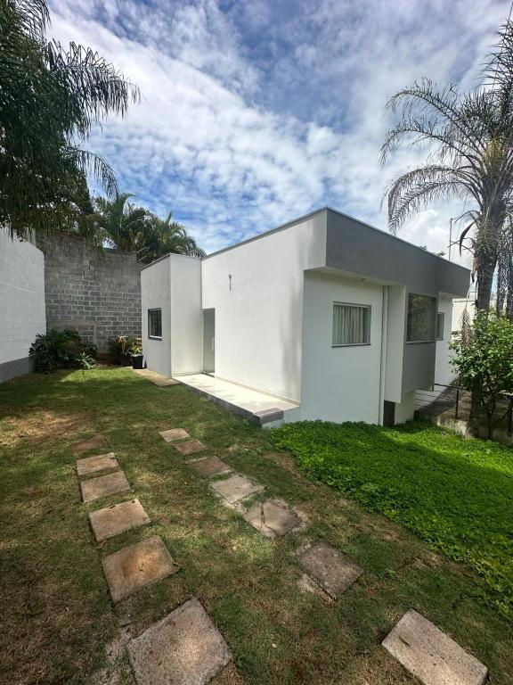 a white house with a grass yard at Casinha da Val in Atibaia