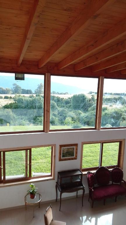 a living room with large windows and a couch at Regreso al Encanto in Puyehue