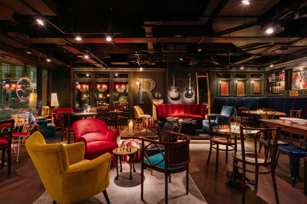 ein Zimmer mit Stühlen und Tischen und Stühlen und ein Zimmer mit Gemälden in der Unterkunft Ruby Lucy Hotel London by IHG in London