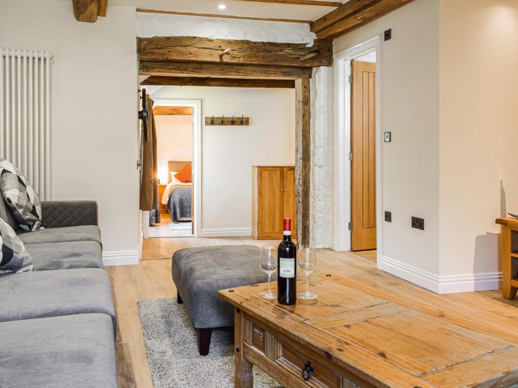 a living room with a bottle of wine on a table at Wheelwright Cottage in Clunbury