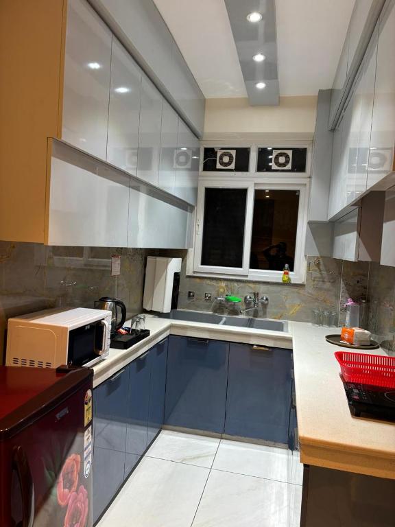 a kitchen with blue cabinets and a microwave at Conifer heights in Shimla