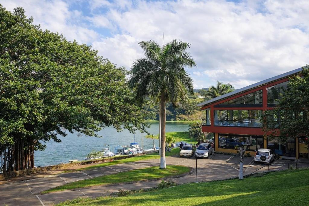 a palm tree in front of a building next to the water at Hotel Puerto San Luis in Tilarán