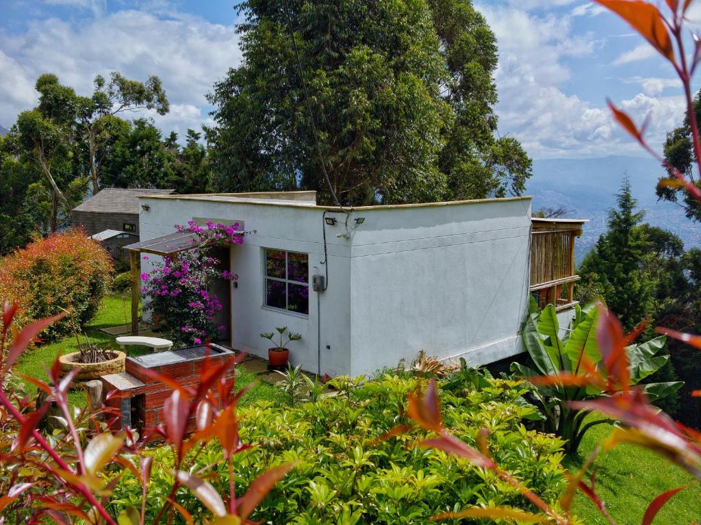 a small white house in a garden with flowers at Green mount in Medellín