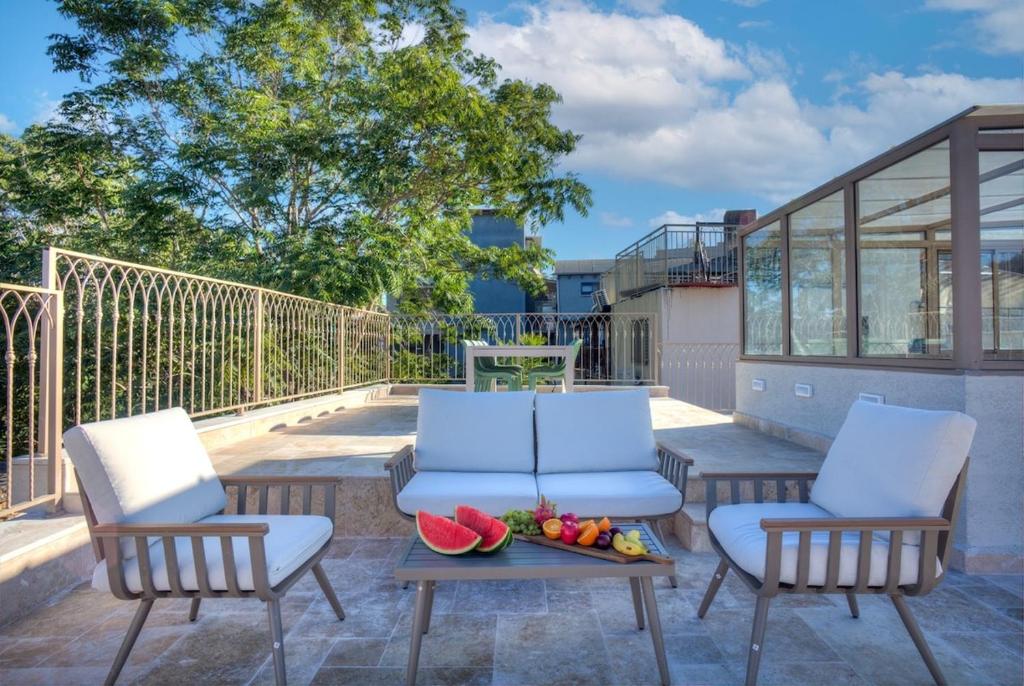 two chairs and a table with fruit on a patio at Keter HaSimta - כתר הסמטה in Safed