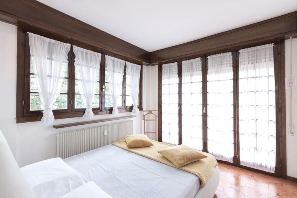 a bedroom with a bed in a room with windows at Maison Leti Comfort Studio in Bellagio