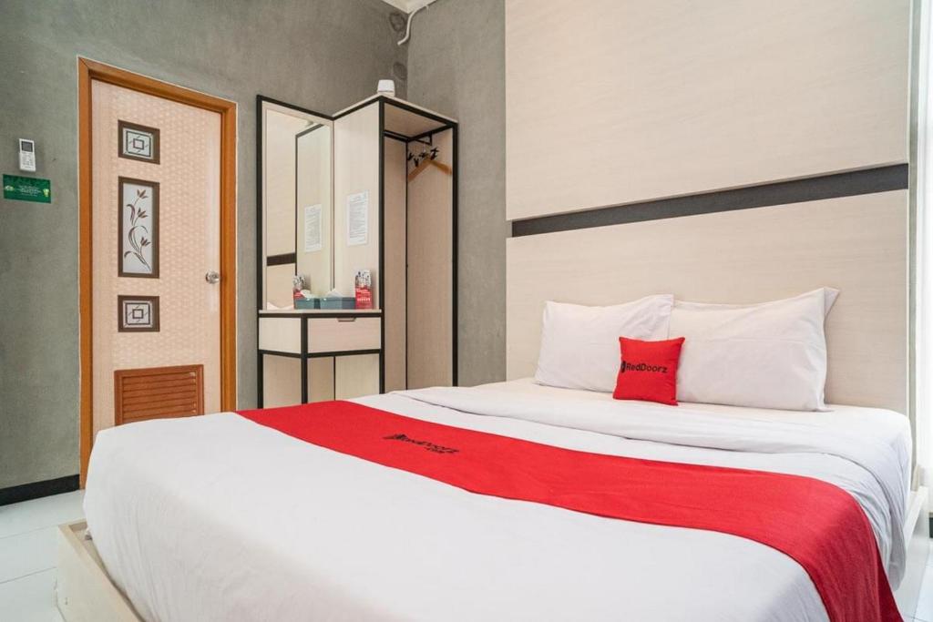 a bedroom with a large white bed with a red pillow at RedDoorz Syariah At Mitra Guest House in Malang