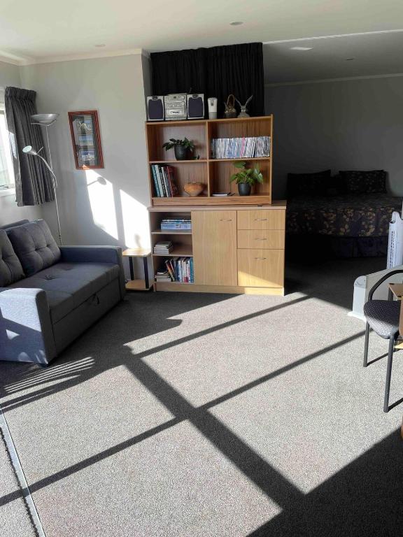 a living room with a couch and a book shelf at Quiet restful unit with seaviews in Auckland