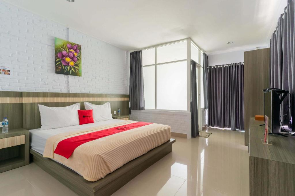 a bedroom with a large bed and a television at RedDoorz Plus @ Vantas Hotel Parbaba in Sinapuran