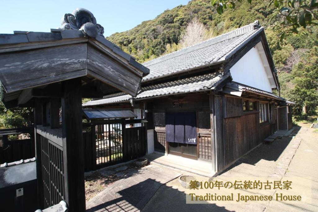 a building with a gate and a mountain in the background at Guesthouse Usagi in Kumano