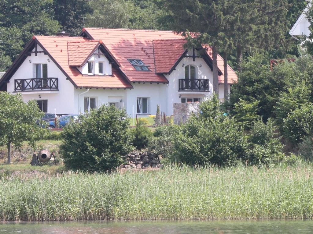 een huis met een rood dak aan de kant van een meer bij Ośrodek Rodzinny in Gwieździn