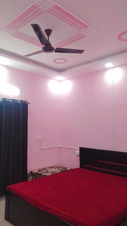 a bedroom with a red bed and a ceiling fan at Laxminarayan Sadan in Ayodhya