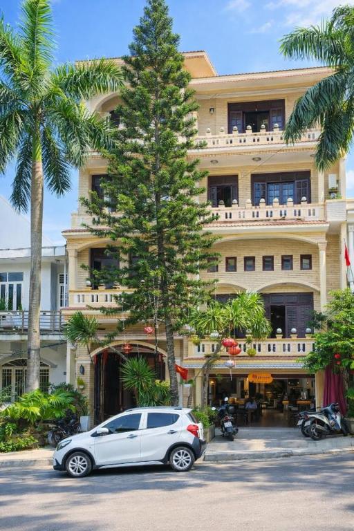 a car parked in front of a building with a palm tree at Perfume Homestay Huế in Hue