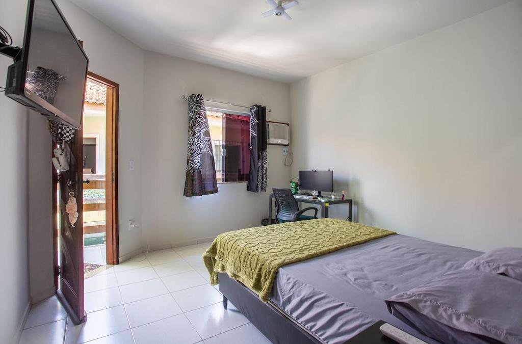a bedroom with a bed and a desk and a window at Casa de Vila Duplex, perto do Centro in Araruama